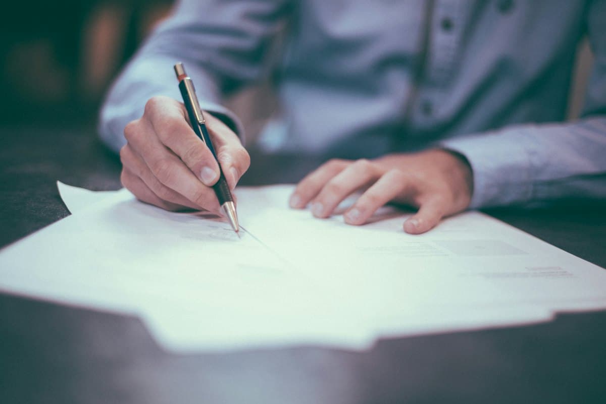 A hand signing a commercial agreement with a pen