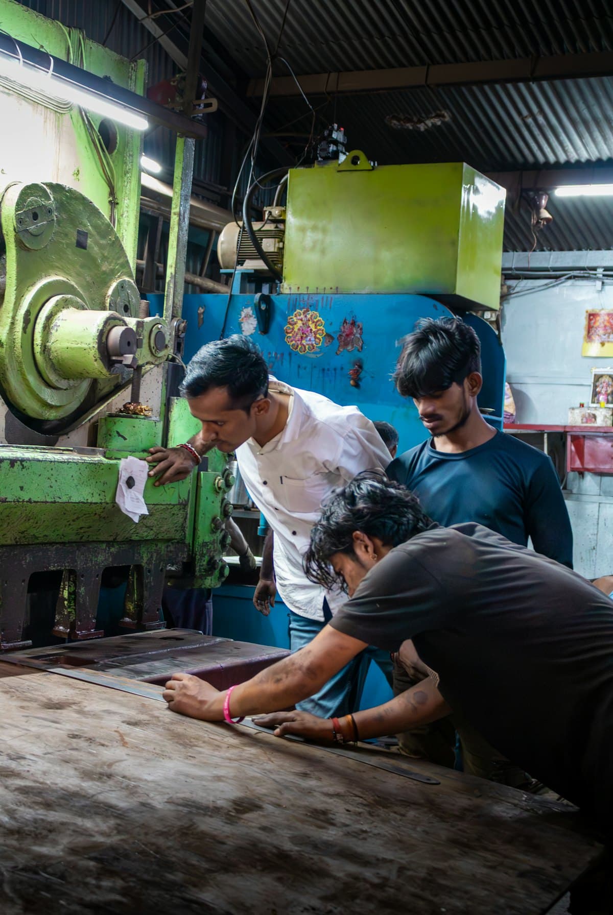 Three men working together at a machine in a small workshop